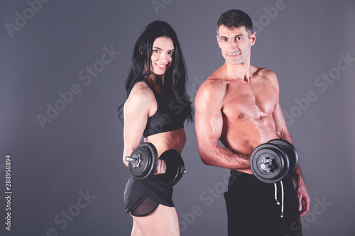 Athletic man and woman with dumb-bells. Personal fitness instructor. Personal training. Weight training. Workout.