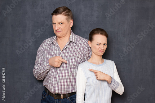 Portrait of annoyed man and woman pointing at one another