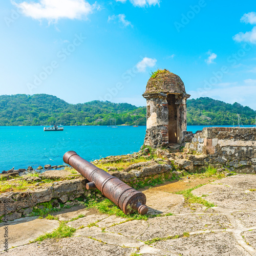 Square photograph of a spanish fort with shooting tower and cannon looking over the bay of Portobelo harbor by the Caribbean sea to protect the spanish customs of pirate attacks, Panama.