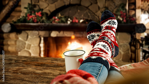 Woman legs with christmas socks and fireplace 