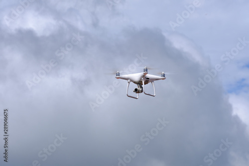 White drone quadcopter flying on the air for take a photo and video with white cloudy background.