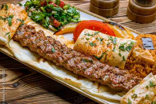 lula kebab spicy with vegetables in Turkish on the board