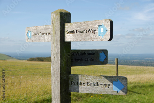 South Downs National Park, Sussex, England, UK. A signpost shows the route of the South Downs Way with views over the Sussex Weald. The South Downs Way is a national trail popular with walkers.