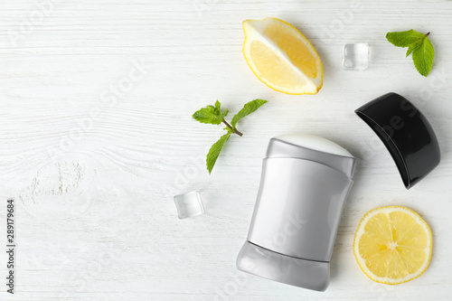 Flat lay composition with stick male deodorant on white wooden table, space for text