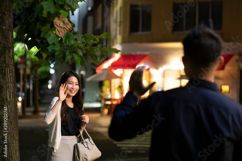 夜の繁華街で待ち合わせをする男女