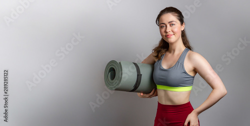 Sport and health. Beautiful slim young woman in sportswear holding a sports Mat. Copy space. Horizontal orientation