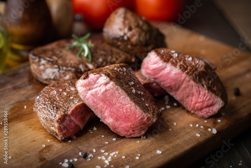rare grilled tenderloin beef steak on cutting board with vegetables