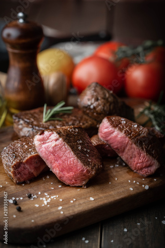 rare grilled tenderloin beef steak on cutting board with vegetables