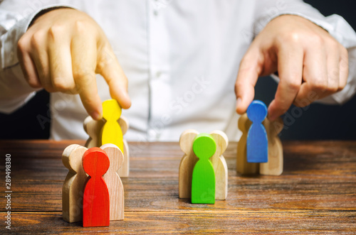 Groups of multicolored wooden people and businessman. The concept of market segmentation. Target audience, customer care. Market group of buyers. Customer relationship management. Selective focus