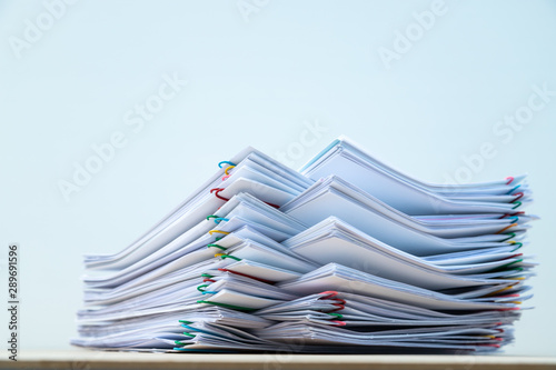 Stack of document paper with colorful paperclip place on wooden table with copy space.