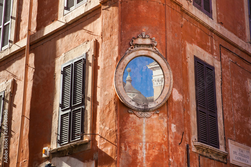 An small piece of the Santa Maria in Aquiro church reflected on a mirror at a corner of Piazza Capranica