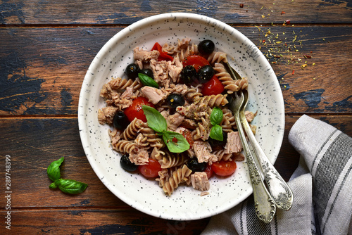 Whole wheat pasta fusilli with tuna, tomato and black olives. Top view with copy space.