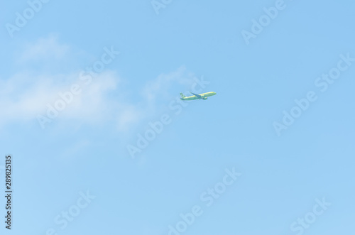 light green plane flies without leaving a trace on the background of the blue sky