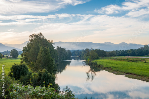 Morning nature landscape with freshwater river and mountains in the distance