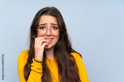 Teenager girl over isolated blue wall nervous and scared