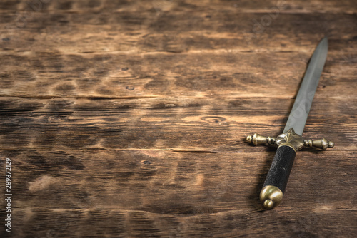 Pirate dagger on a brown wooden table background with copy space.