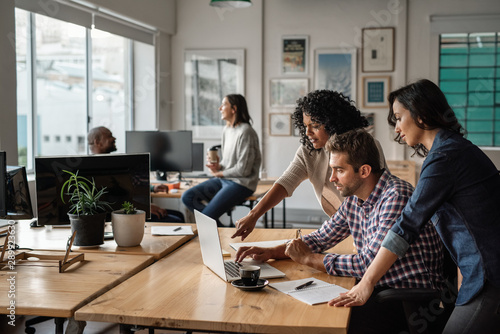 Three young designers using a laptop together at work