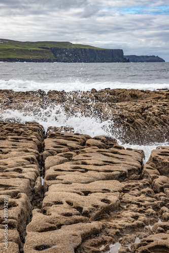 Harbour beach with waves and Cliffs of Moher in background