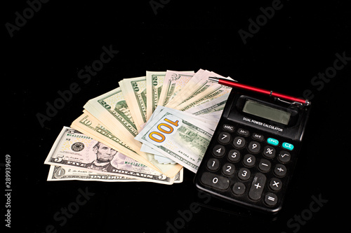 Dólares en billetes, calculadora y bolígrafo.