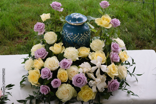 funeral and mourning concept - flowers surrounding urn 