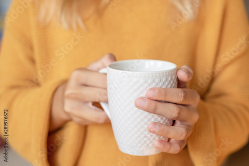cosy autumn - cup of tea in girl's hands and autumn leaves