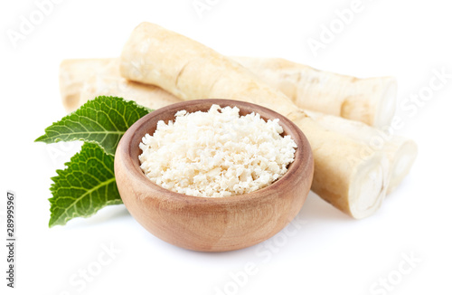 Horseradish root and grated horseradish in wooden plate on white background