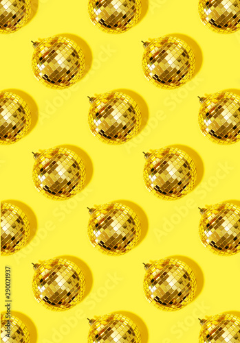 New year baubles. Shiny gold disco balls on yellow background. Pop disco style attributes, retro concept. Creative Christmas pattern. Flat lay, top view.