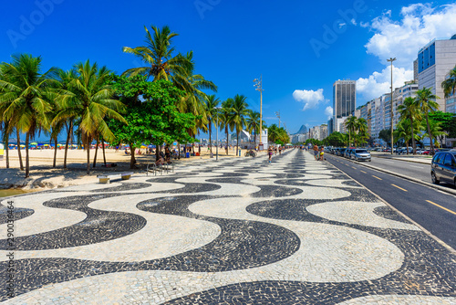 View of Copacabana beach with palms and mosaic of sidewalk in Rio de Janeiro, Brazil. Copacabana beach is the most famous beach in Rio de Janeiro. Sunny cityscape of Rio de Janeiro