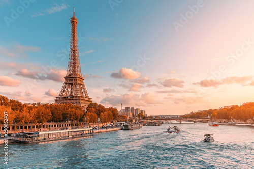 Główną atrakcją Paryża i całej Europy jest wieża Eiffla w promieniach zachodzącego słońca nad brzegiem Sekwany z wycieczkowymi statkami turystycznymi