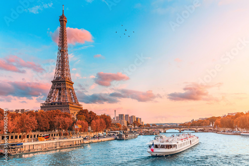 Główną atrakcją Paryża i całej Europy jest wieża Eiffla w promieniach zachodzącego słońca nad brzegiem Sekwany z wycieczkowymi statkami turystycznymi