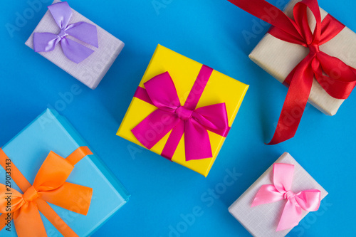 Multi-colored gift boxes with bright bows on the blue background. Top view.