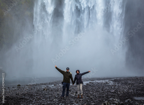skógafoss, Iceland »; August 2017: A couple of young people under the great waterfall shake hands