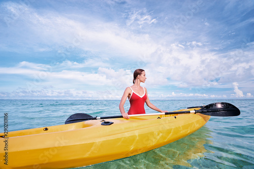 Young woman holding the sea kayak in the tropical calm lagoon.
