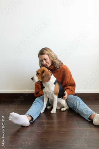 Girl in a sweater at home plays with a dog