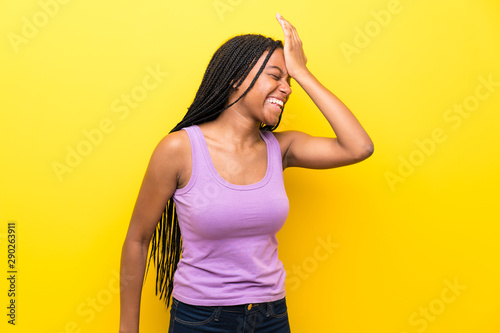 African American teenager girl with long braided hair over isolated yellow wall has realized something and intending the solution
