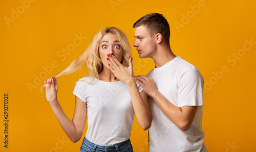 Guy whispering secret or gossip to surprised girl