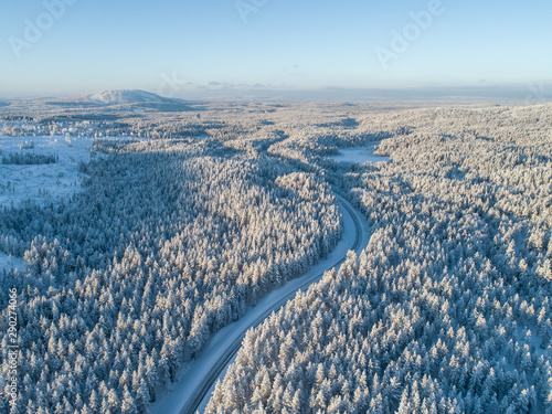 Curvy road in the middle of dense taiga at winter day in lapland, Finland