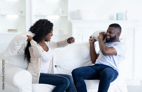Playful Black Couple Fighting By Pillows, Having Fun At Home