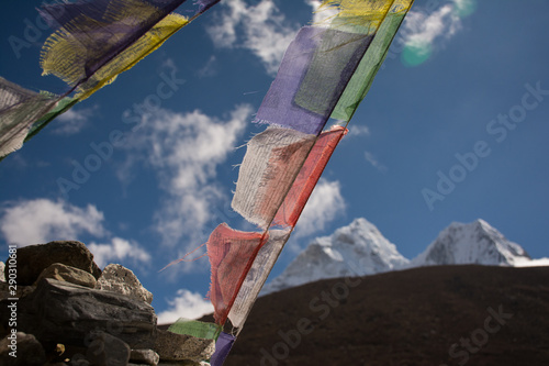Colorful prayer flags in Nepal with clear sky and snow mountain background.