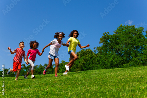 Group of friends children run fast in the park
