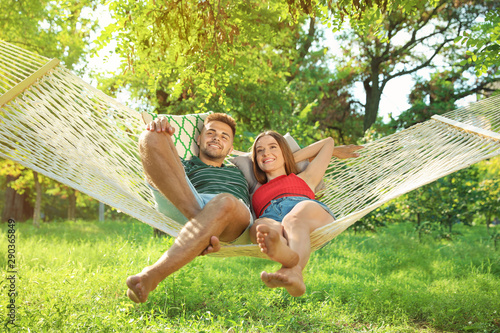 Young couple resting in comfortable hammock at green garden