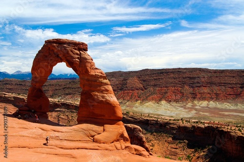 View on red isolated red sandstone arch with rugged stone valley background - Delicate arch, Arches national park, Utah