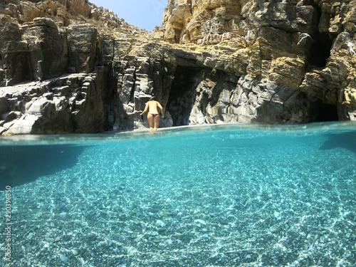 Above and below underwater photo of crystal clear sea paradise rocky seascape full of caves beach of Mouros, Amorgos island, Cyclades, Greece