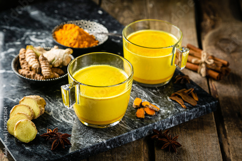 Turmeric golden milk and ingredients on wood background, copy space