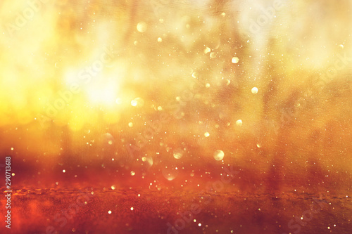 Abstract background of light burst among trees and glitter golden bokeh lights