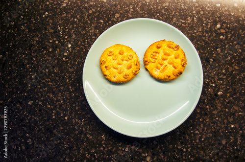 Almond biscuits on a blue plate making up a smiling face