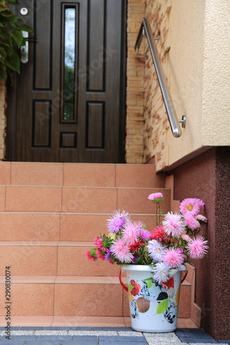 Piękna kolorowa dekoracja z kolorowych kwiatów i wiaderka na schodach domu. 