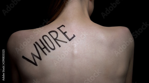 Insecure naked female showing word whore on shoulder, public humiliation