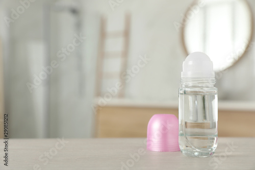 Open female roll-on deodorant on wooden table in bathroom. Space for text