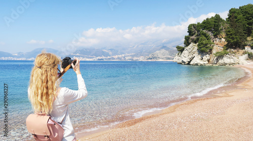Girl with curly hair looking and photographs the sea in Montenegro.